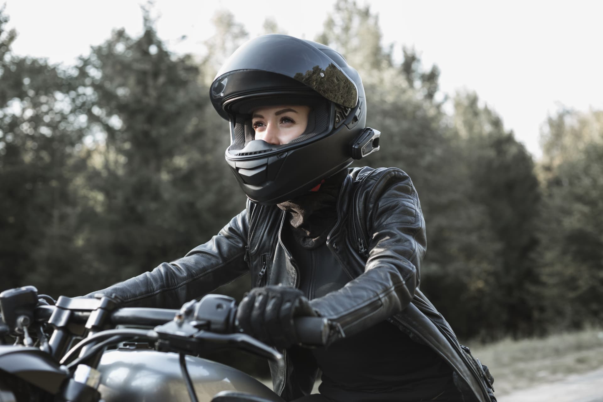 A rider in a helmet and leather jacket on a motorcycle