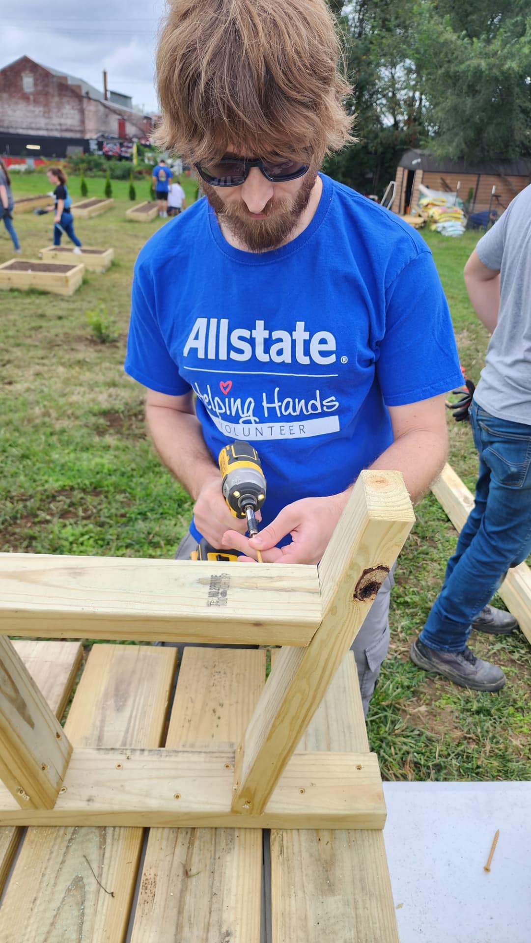 Agency team member assembling a raised garden bed at a community garden build