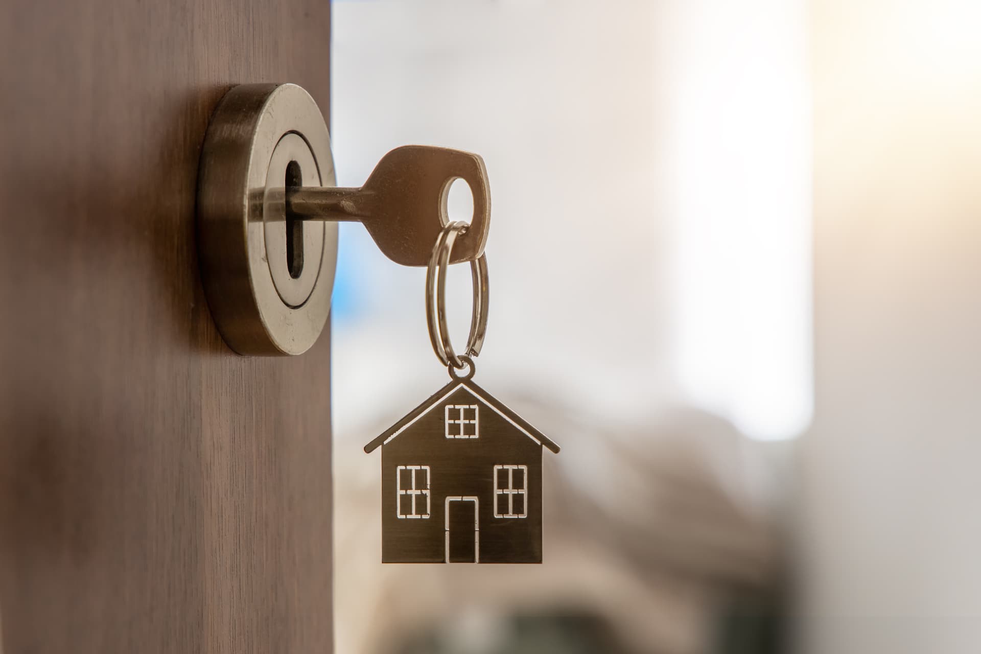 A key with a house keychain in a front door lock