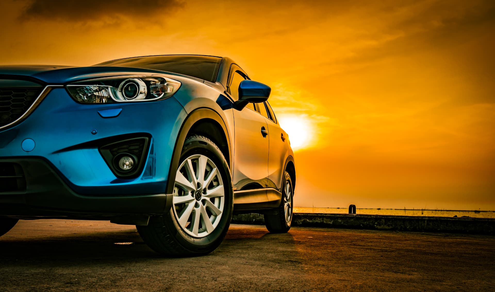 A blue SUV parked at sunset