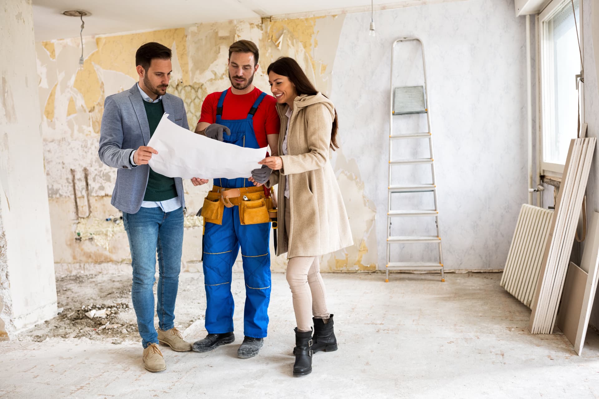 An owner, a contractor and an agent reviewing plans inside a property under renovation