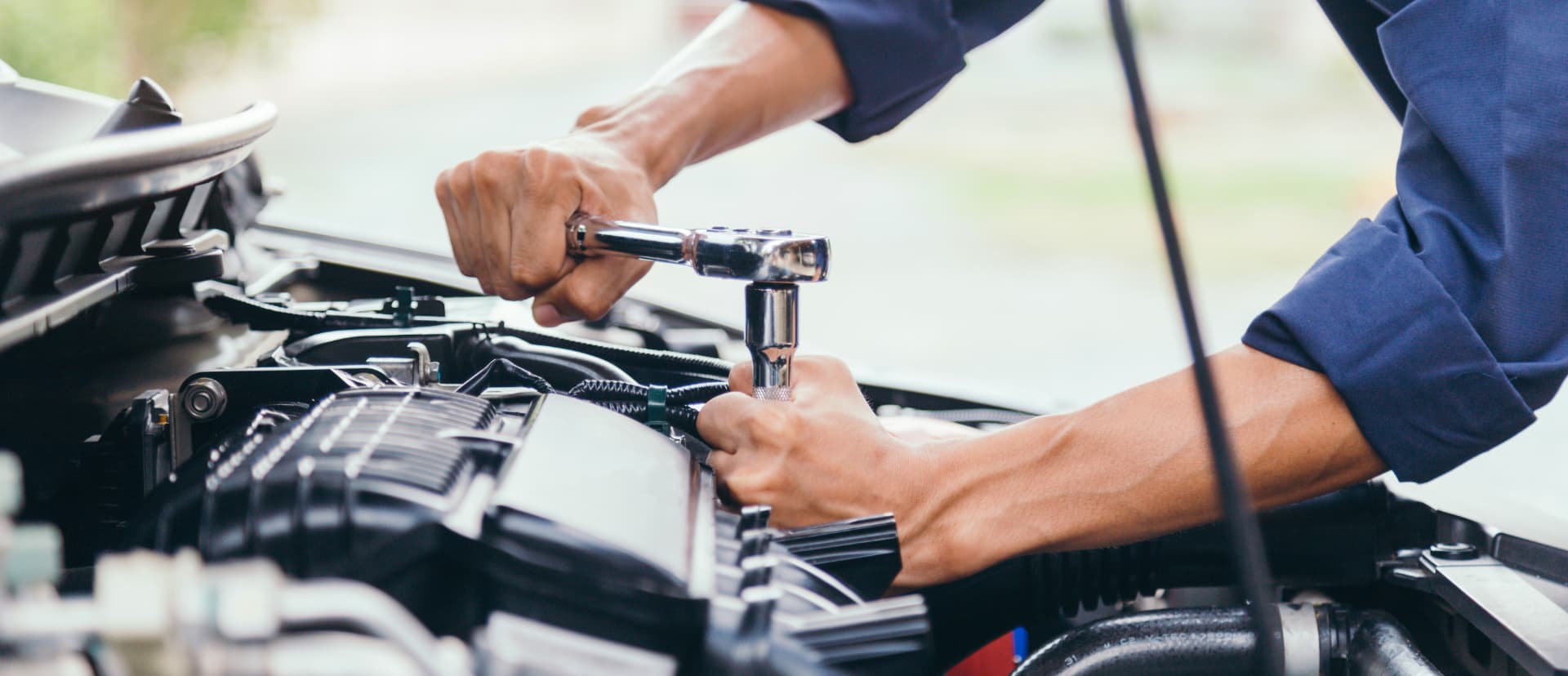 A technician working under the hood of a vehicle at a repair shop